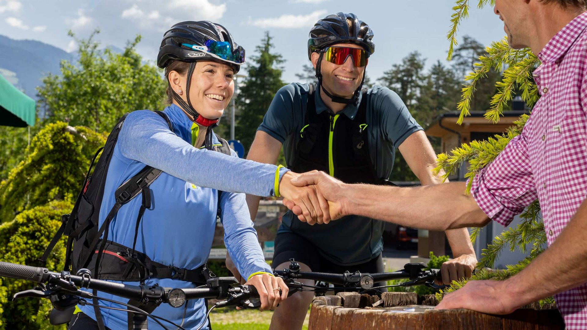Tauernradweg © Brunner Images Zwei Radfahrer grüßen freundlich und schütteln die Hand eines Mannes im Freien