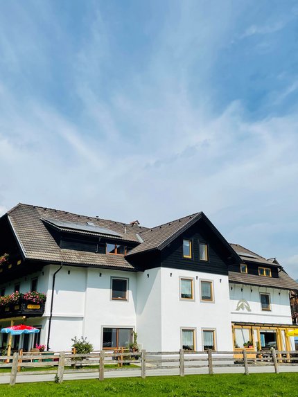 Großes weißes Haus mit braunem Dach und Berglandschaft im Hintergrund