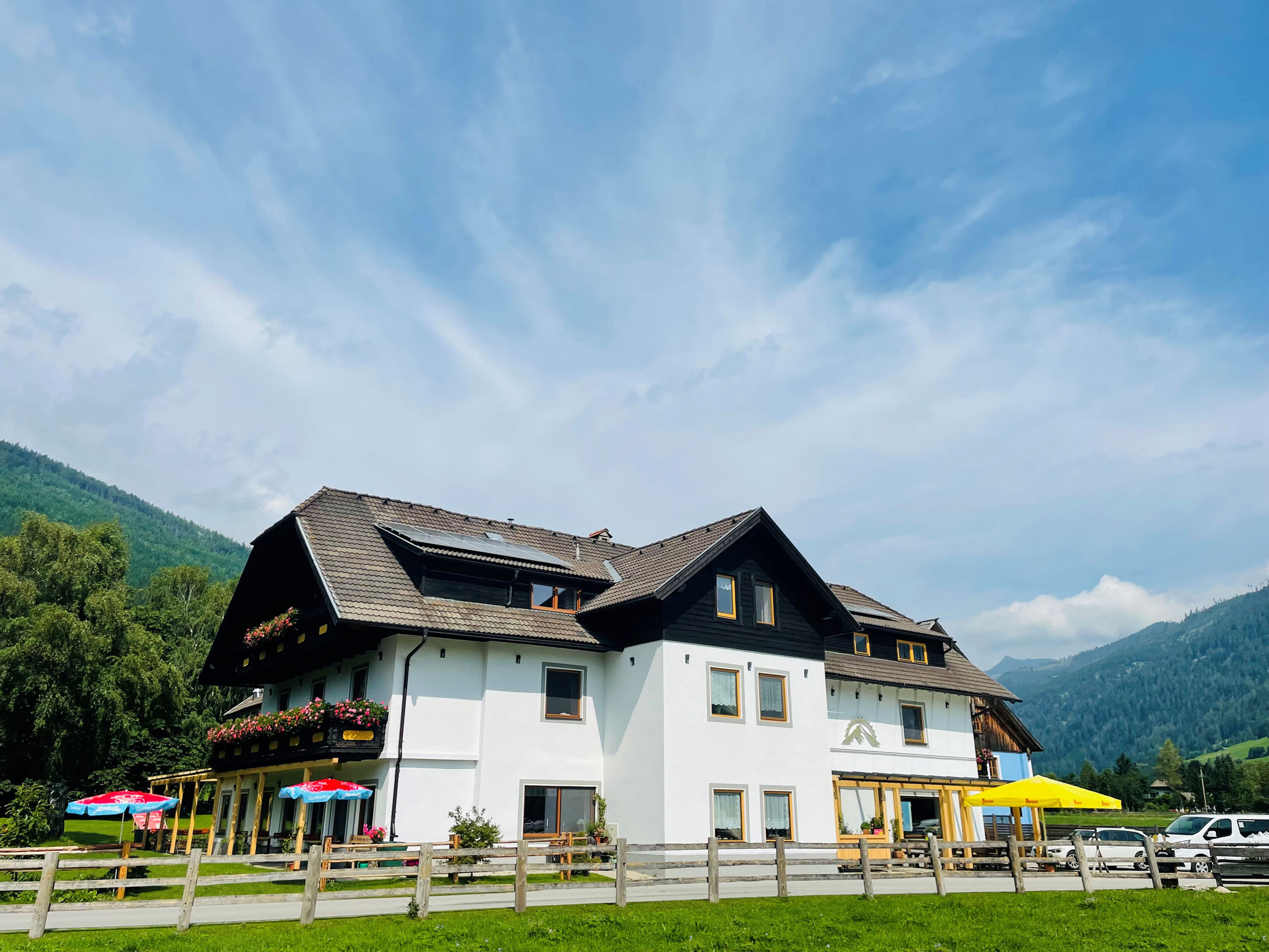 Landhaus Lungau © Landhaus Lungau Großes weißes Haus mit braunem Dach und Berglandschaft im Hintergrund